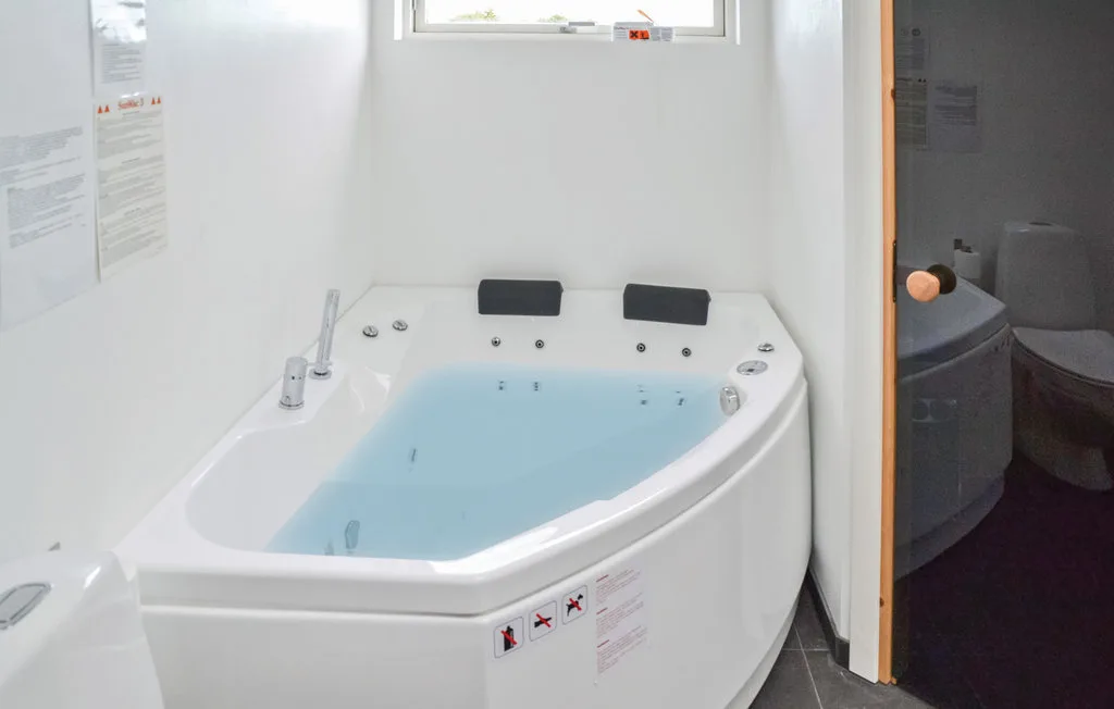 Un baño con una bañera de esquina llena de agua.