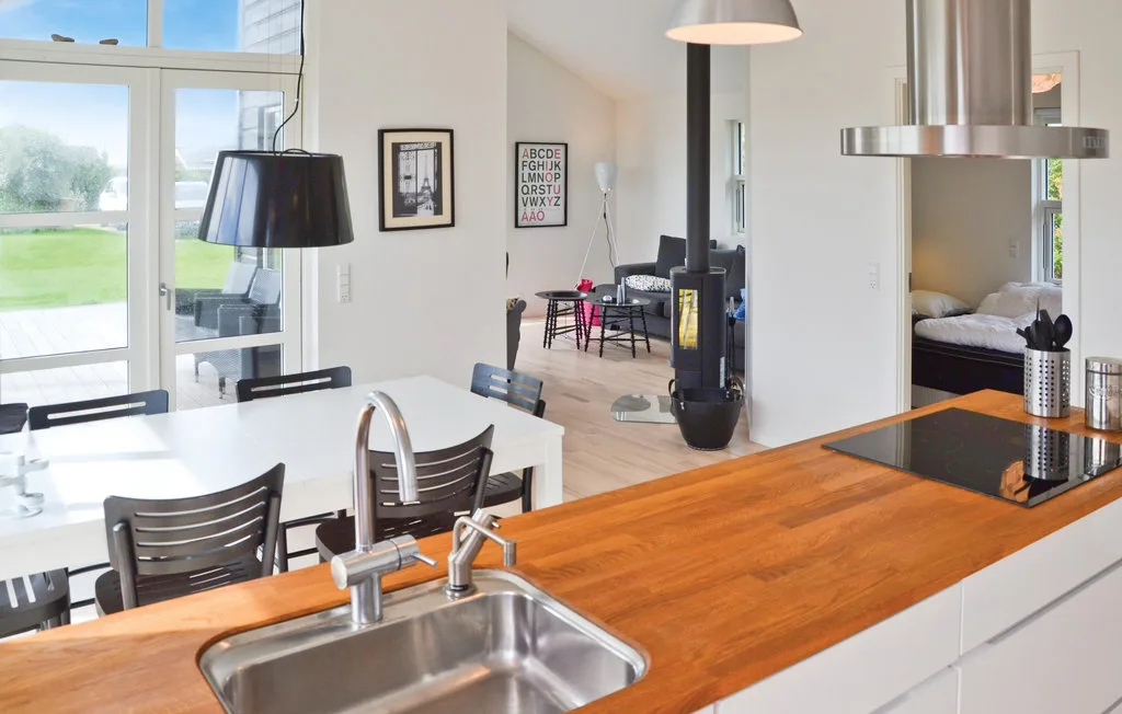 Una luminosa cocina y comedor de concepto abierto con una isla de madera y fregadero de acero inoxidable.