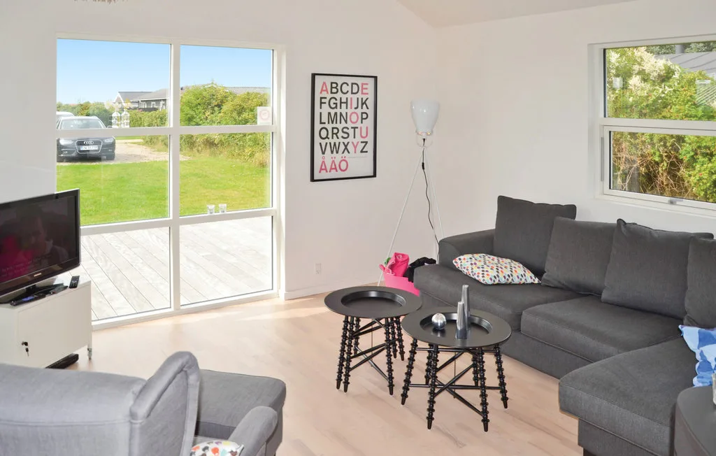 Una sala luminosa con asientos grises y dos mesas redondas pequeñas.