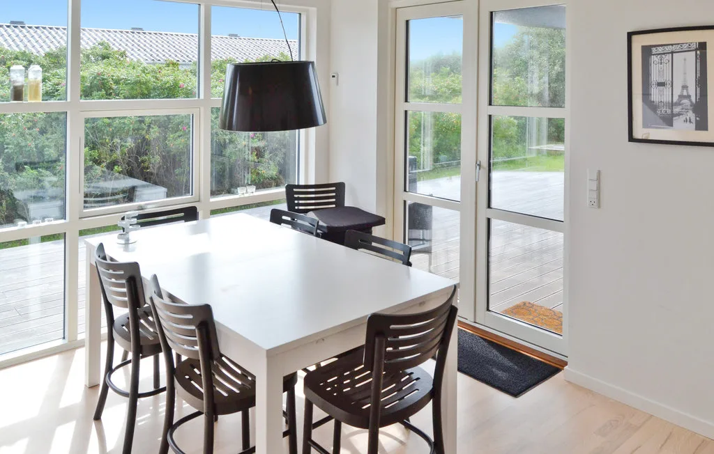 Un comedor luminoso con una mesa grande junto a amplias ventanas y puertas de vidrio.