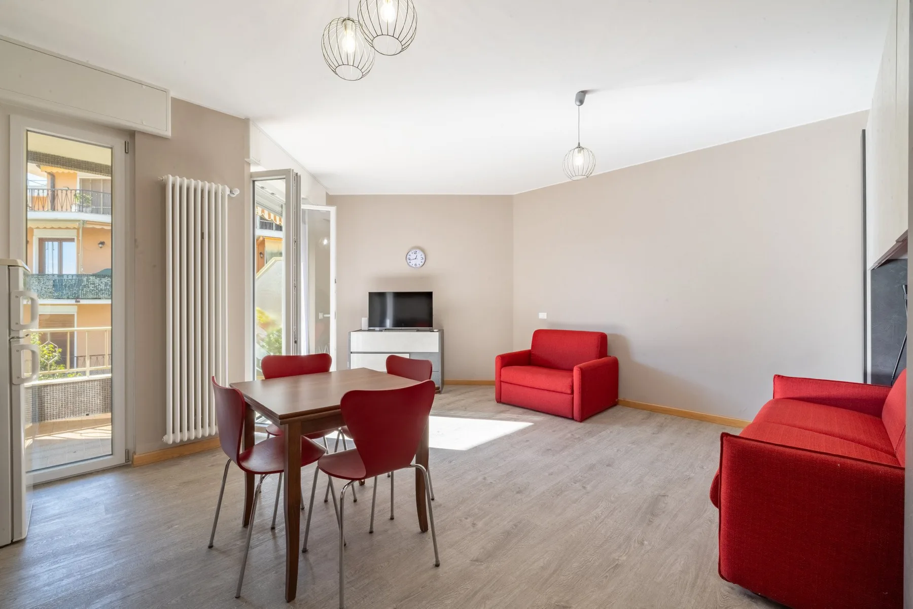 Una luminosa sala de estar y comedor con asientos rojos y una mesa de madera.