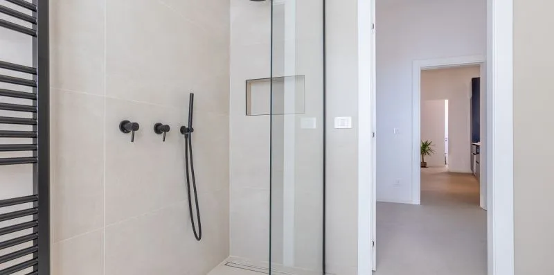 A bathroom shower with a glass screen opens onto a hallway.