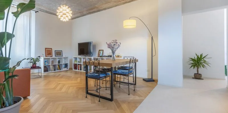 A dining area with a table and chairs beside a bright open living space.