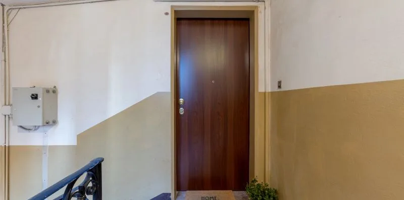 An interior hallway with a closed wooden door and a stair railing.