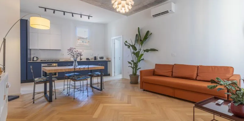 A living room with an orange sofa and an open kitchen.