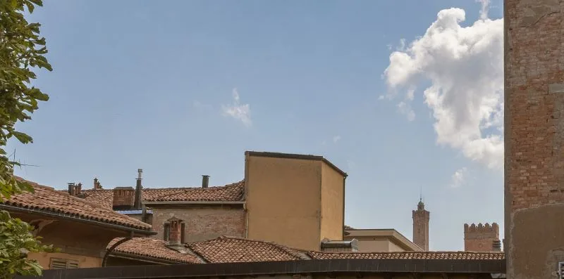 A view of tiled rooftops and historic brick buildings beneath a partly cloudy sky.