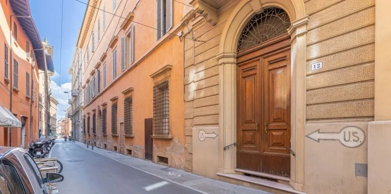 A narrow street lined with pastel buildings and a large wooden doorway.