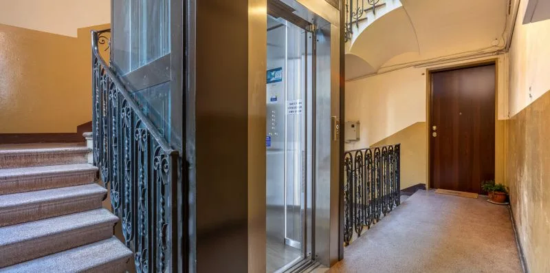 An interior stairwell with a glass elevator and a hallway.