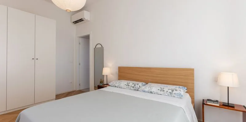 A bright bedroom with a neatly made bed and a wooden headboard.