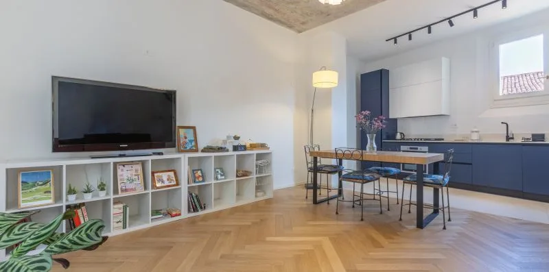 A bright open-plan kitchen and dining area with a television on a low shelf.
