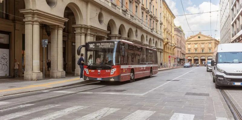 A city street with a red tram passing historic buildings.