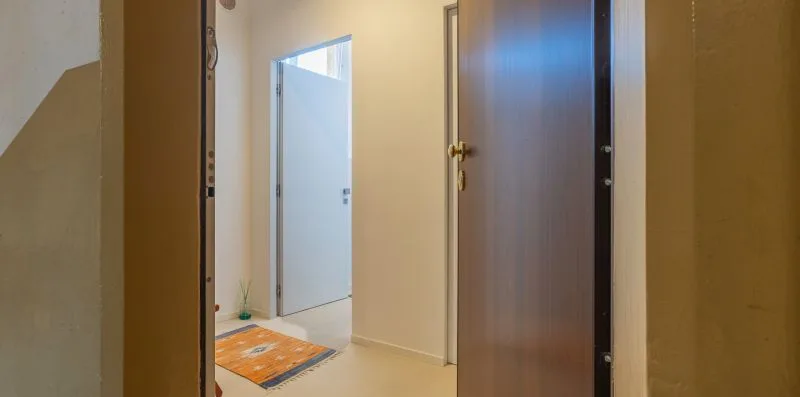 A hallway with an open doorway and a small orange rug.