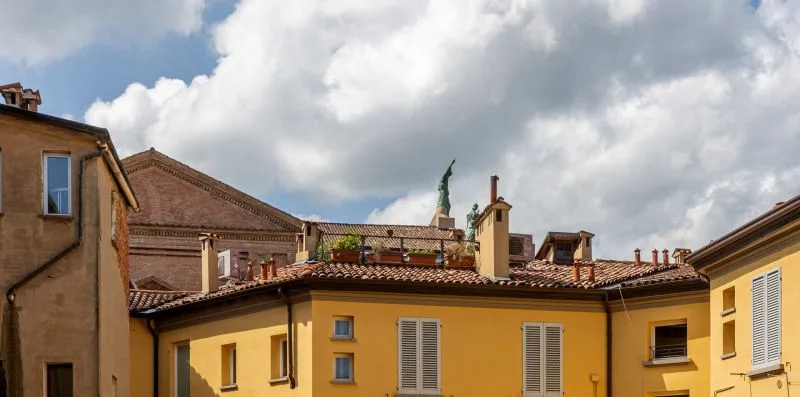 A row of yellow buildings with tiled roofs beneath a cloudy sky.