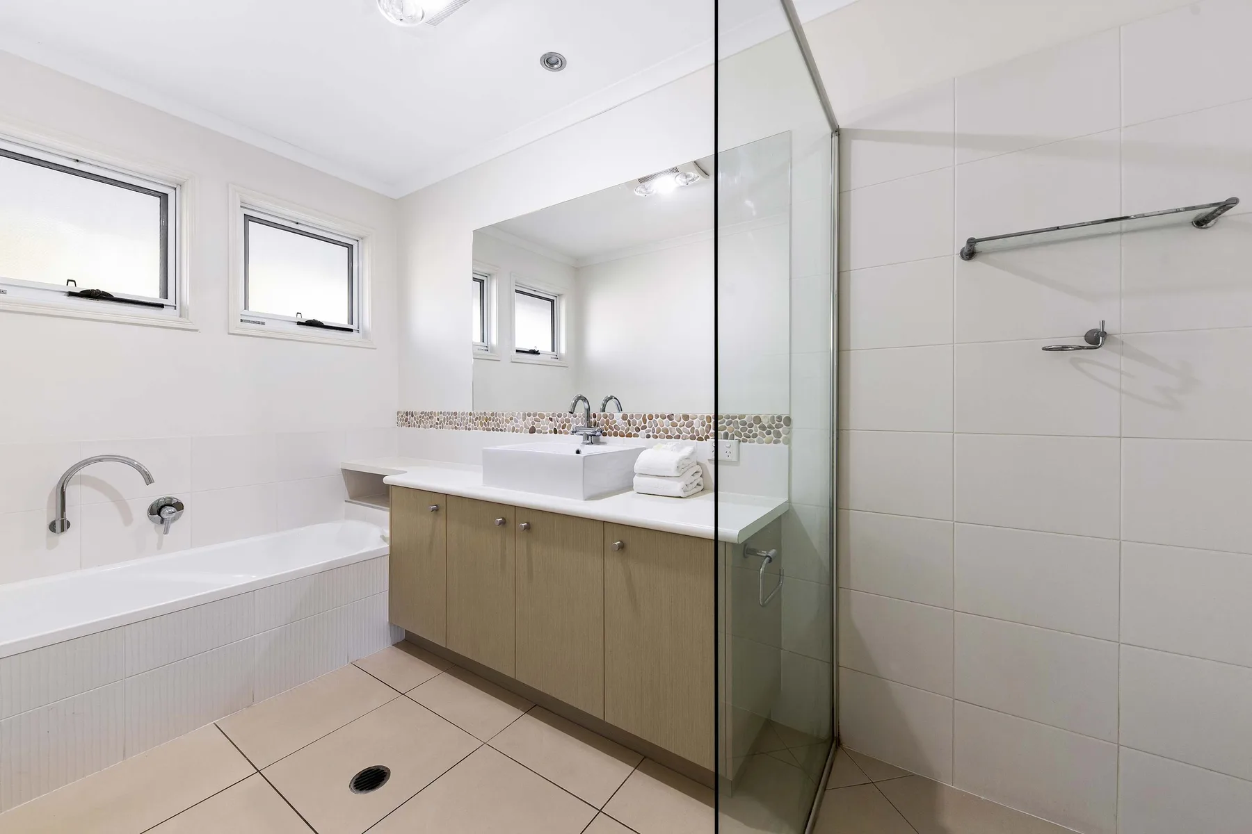 A bright bathroom with a bathtub, vanity, and shower.