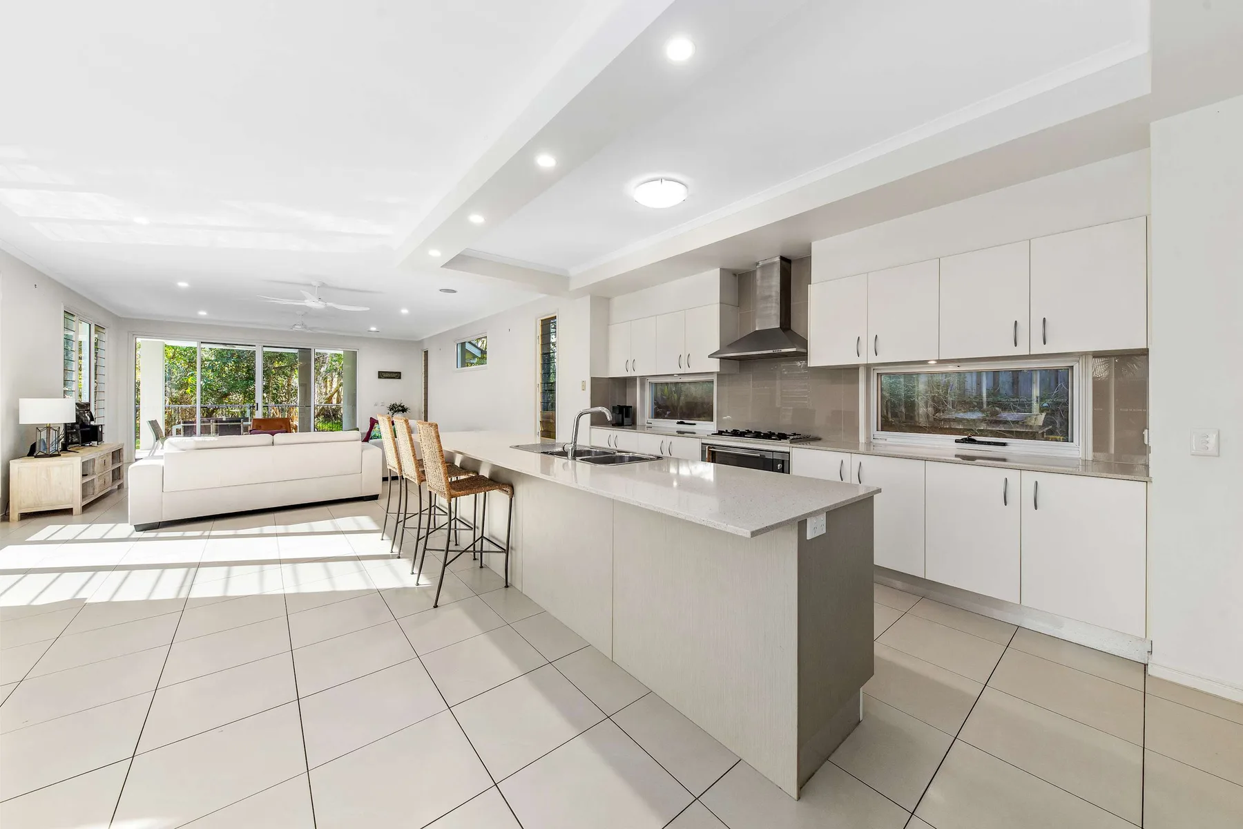 Open-plan kitchen and living area with a white island and seating.