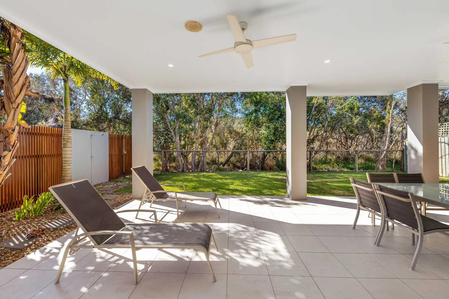 Covered patio with outdoor seating overlooking a fenced garden.