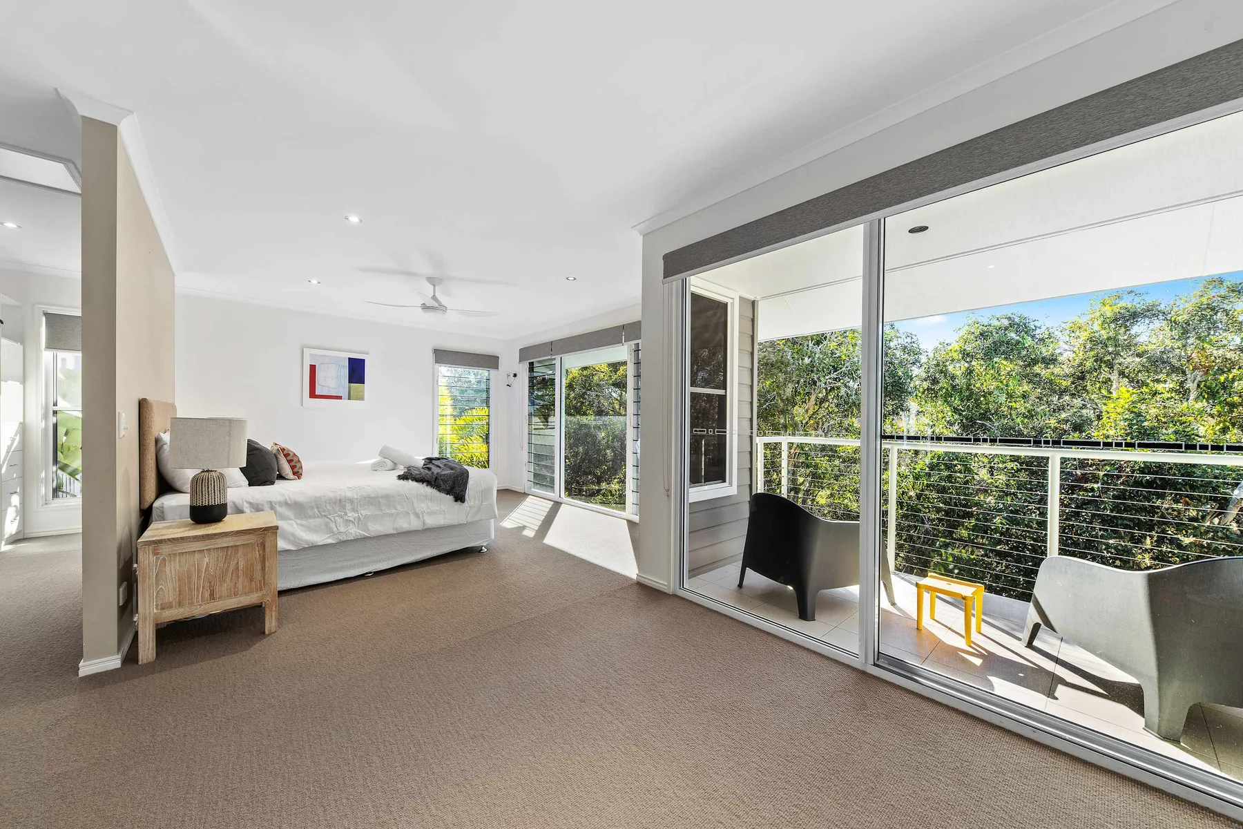 A bright bedroom opens onto a balcony through wide glass doors.
