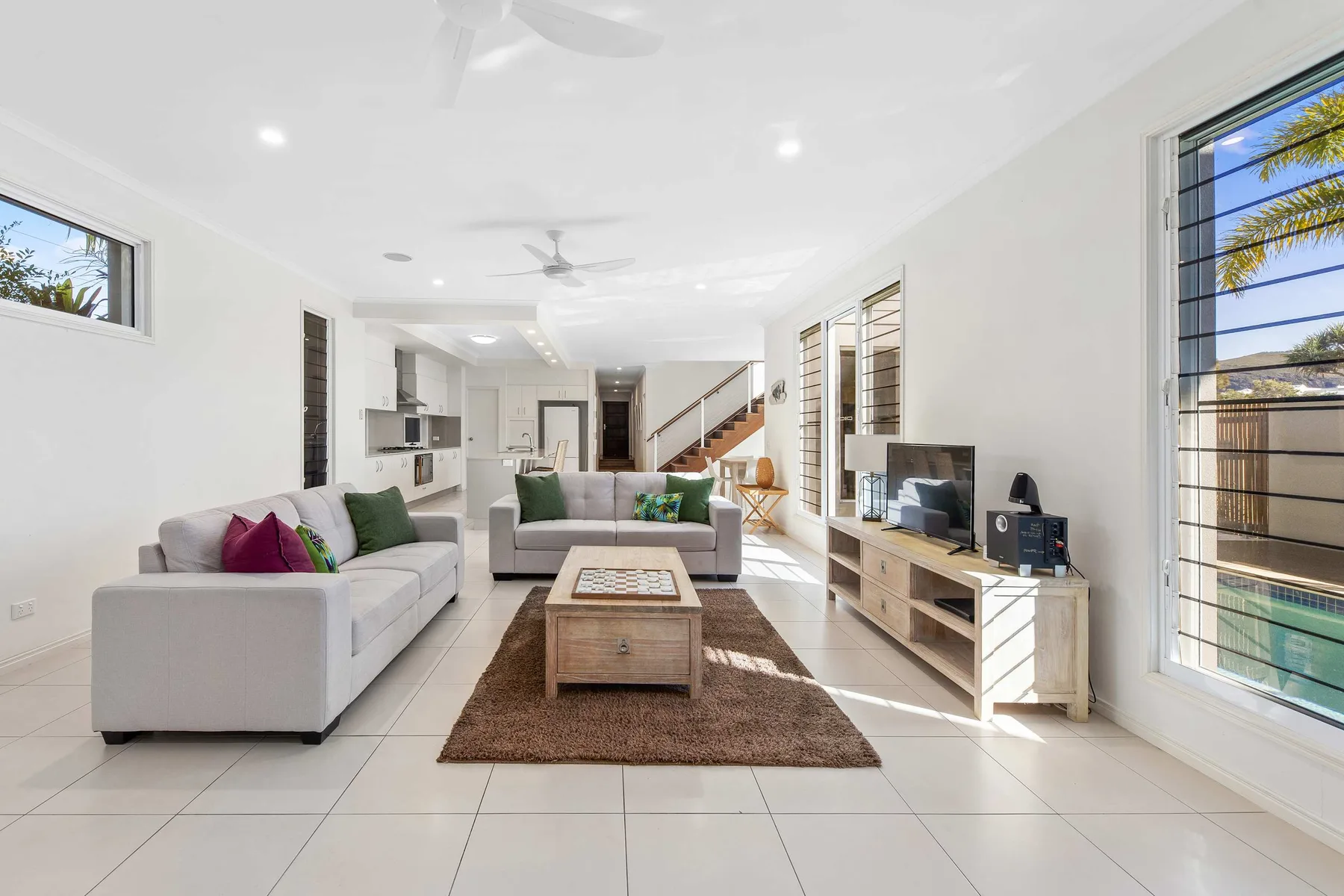 Bright living room with seating, a television, and large windows.