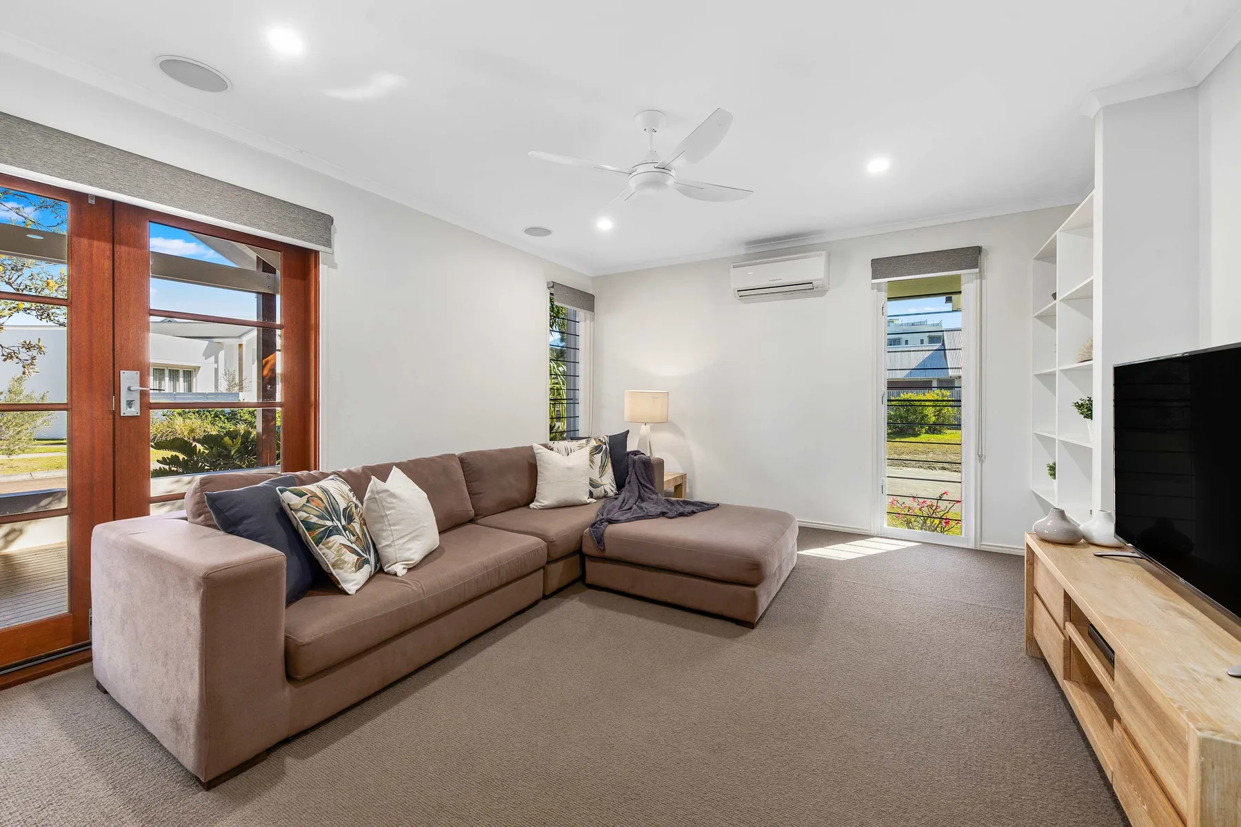 A bright living room with a sectional sofa and large windows.