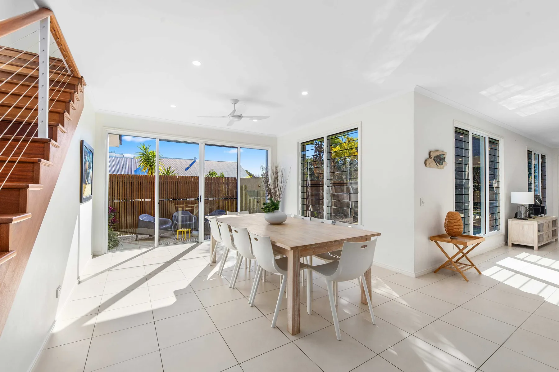 A bright dining area with a wooden table beside large windows.