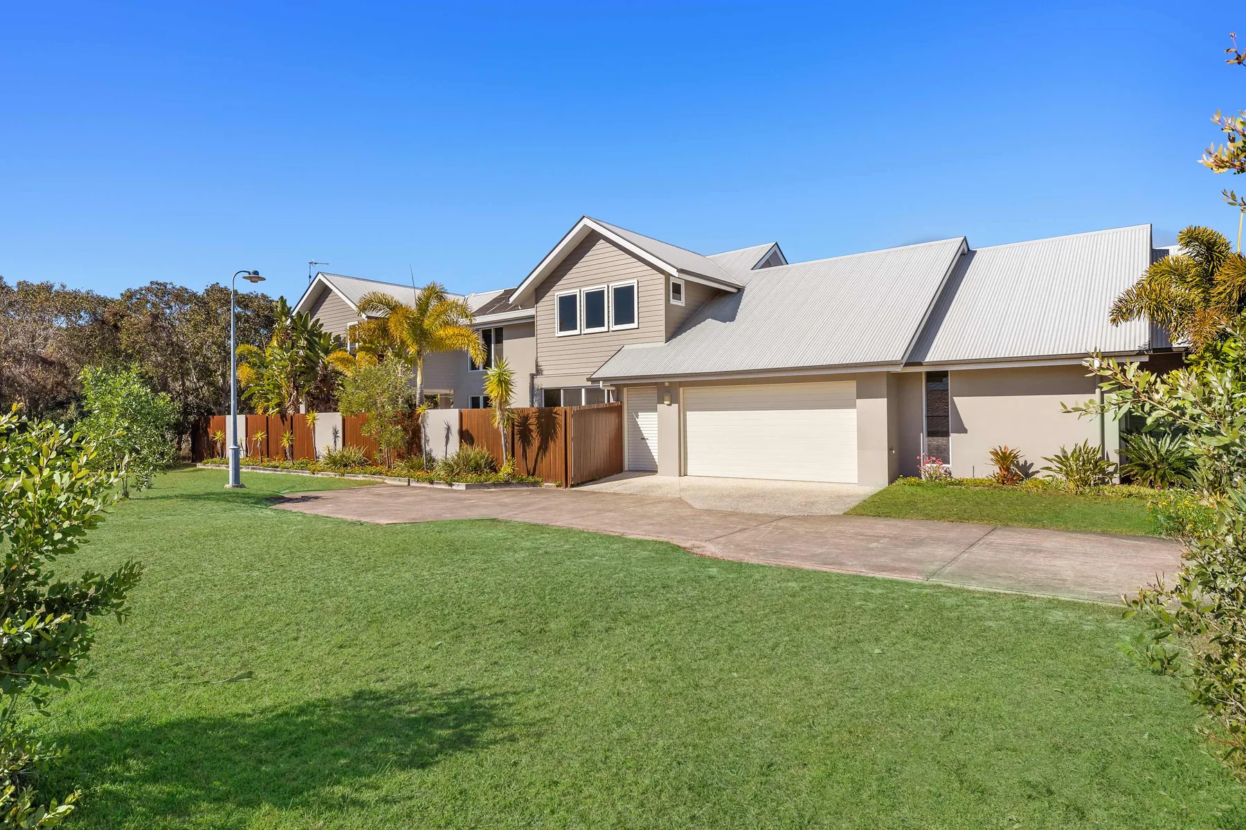 A large house with a lawn and driveway under a clear blue sky.