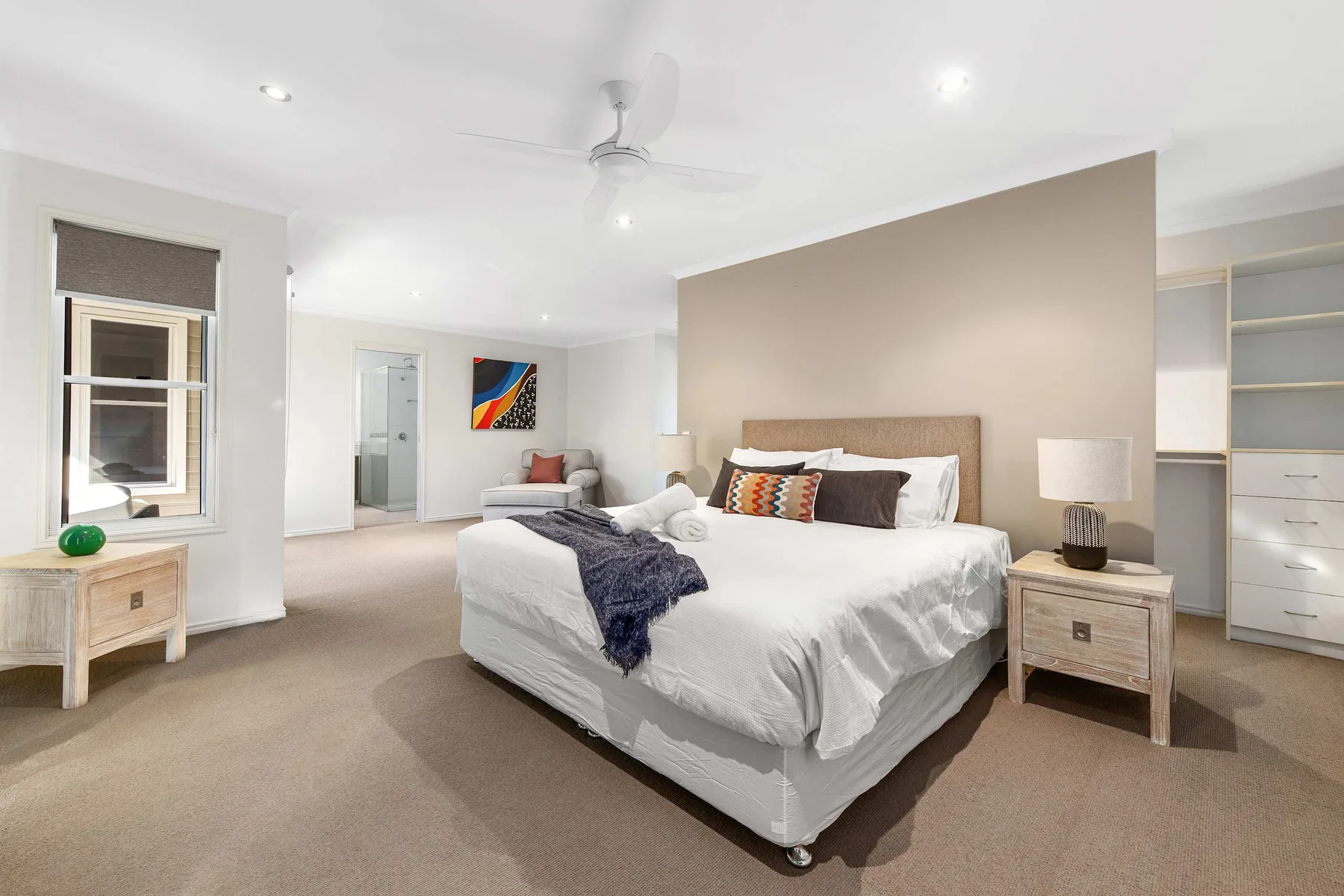 A bright bedroom with a neatly made bed and bedside tables.