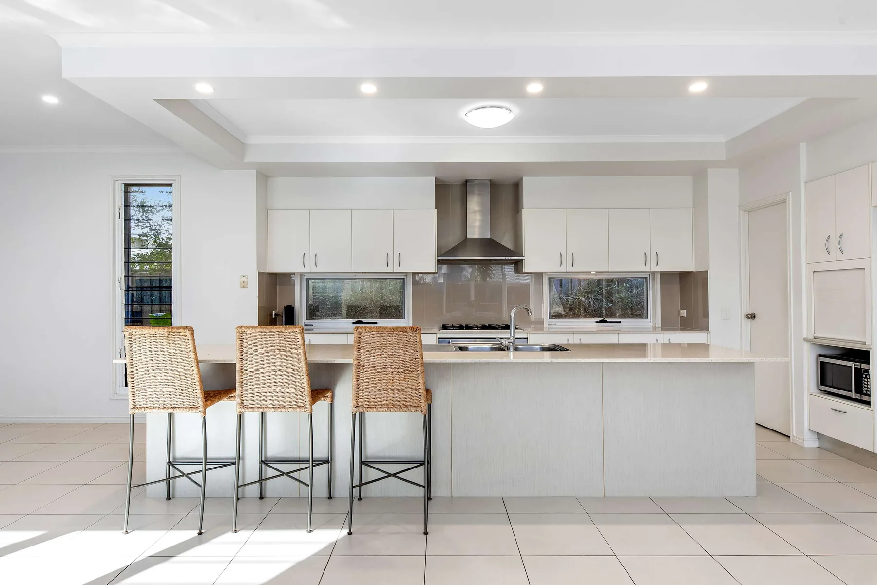 A bright kitchen with a central island, bar seating, and white cabinetry.
