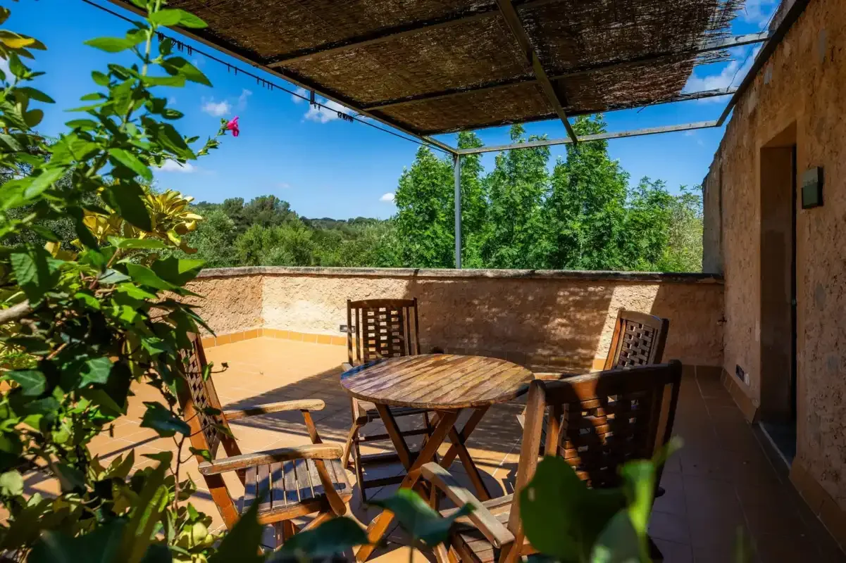 A shaded outdoor dining area with a wooden table and chairs.