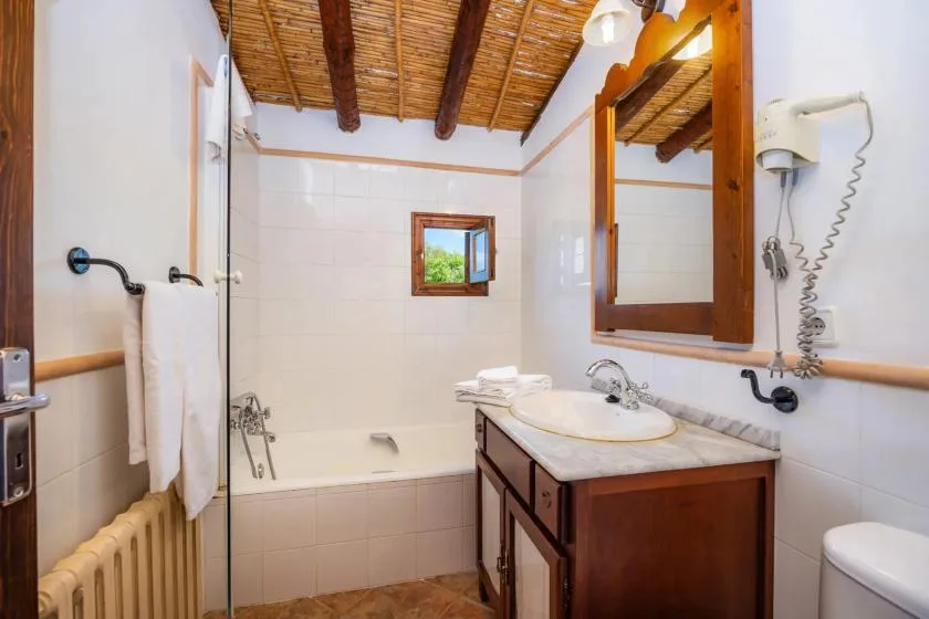 A tiled bathroom with a bathtub, sink, and wooden ceiling.