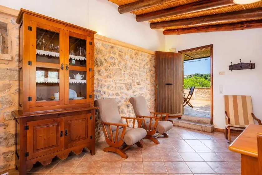 A rustic dining room with wooden seating and an open doorway to a patio.