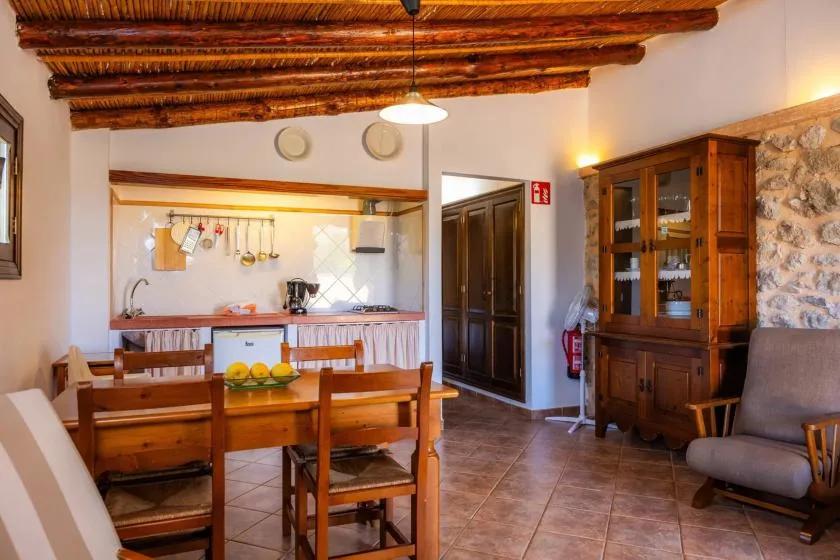 A dining area with a wooden table and chairs beside an open kitchen.