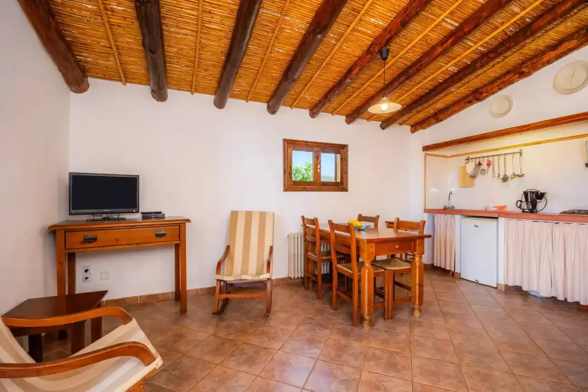 A dining and sitting area with a wooden table, chairs, and a television.