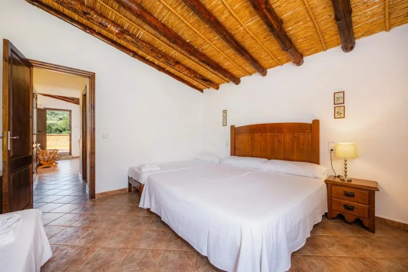 A bedroom with a large bed beneath a wooden-beam ceiling.