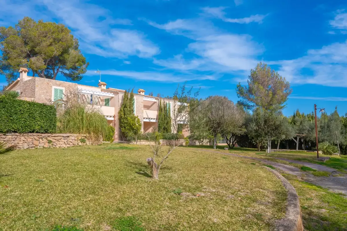 A low stone building stands beside a grassy lawn and curving path.