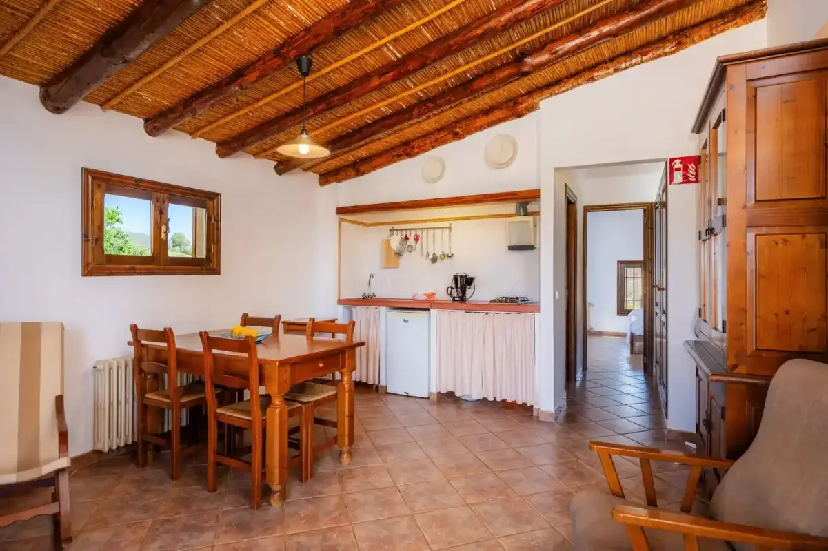 A dining area with a wooden table and chairs beneath a beamed ceiling.