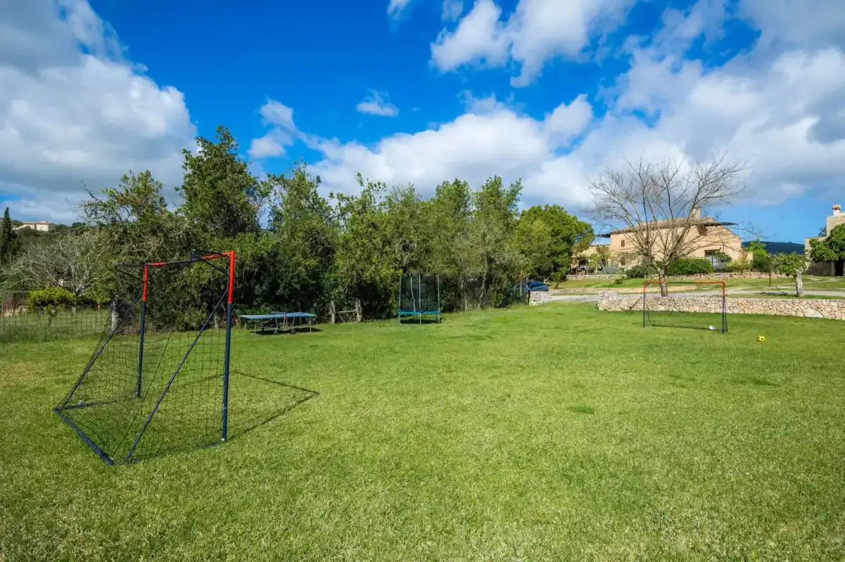 A grassy outdoor recreation area with sports equipment and trees.
