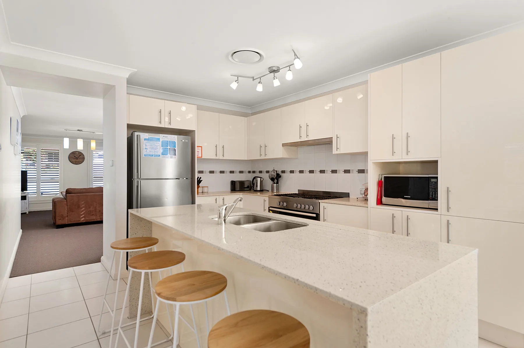 A bright kitchen with a long island, stainless steel appliances, and light cabinetry.