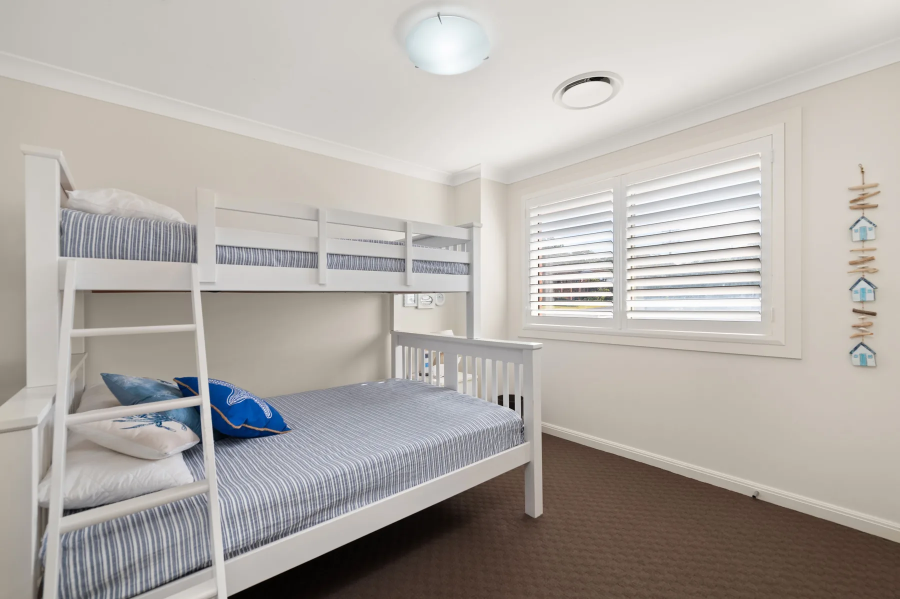 A bedroom with bunk beds and a window with white blinds.