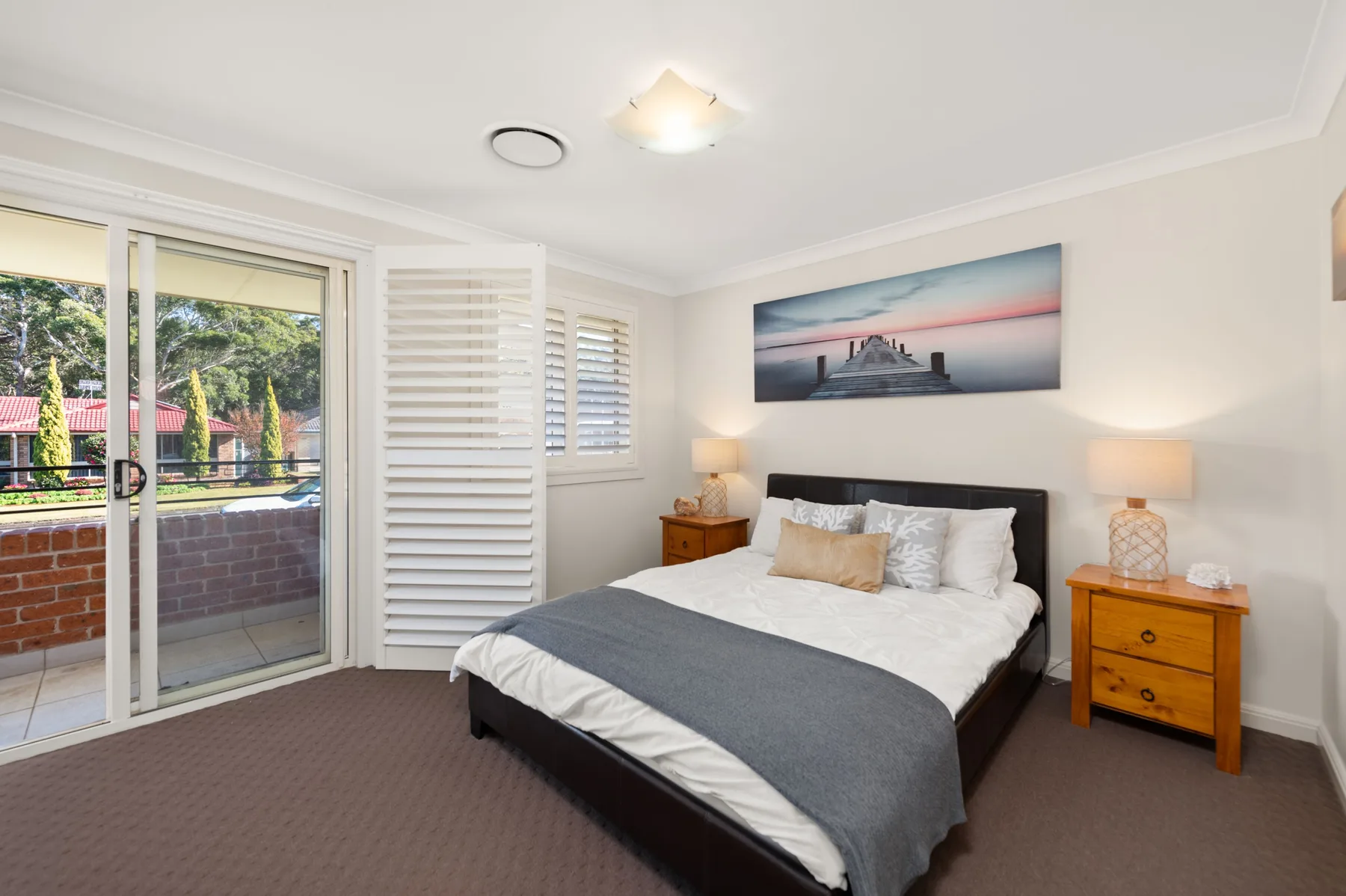 A bedroom with a bed, bedside tables, and sliding glass doors.
