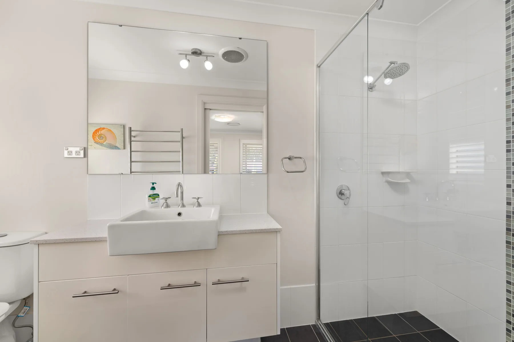 A bright bathroom with a vanity and glass-enclosed shower.