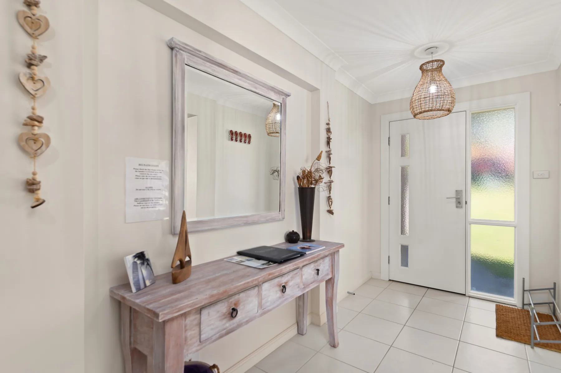 A bright entryway with a console table, wall mirror, and glass-panel door.