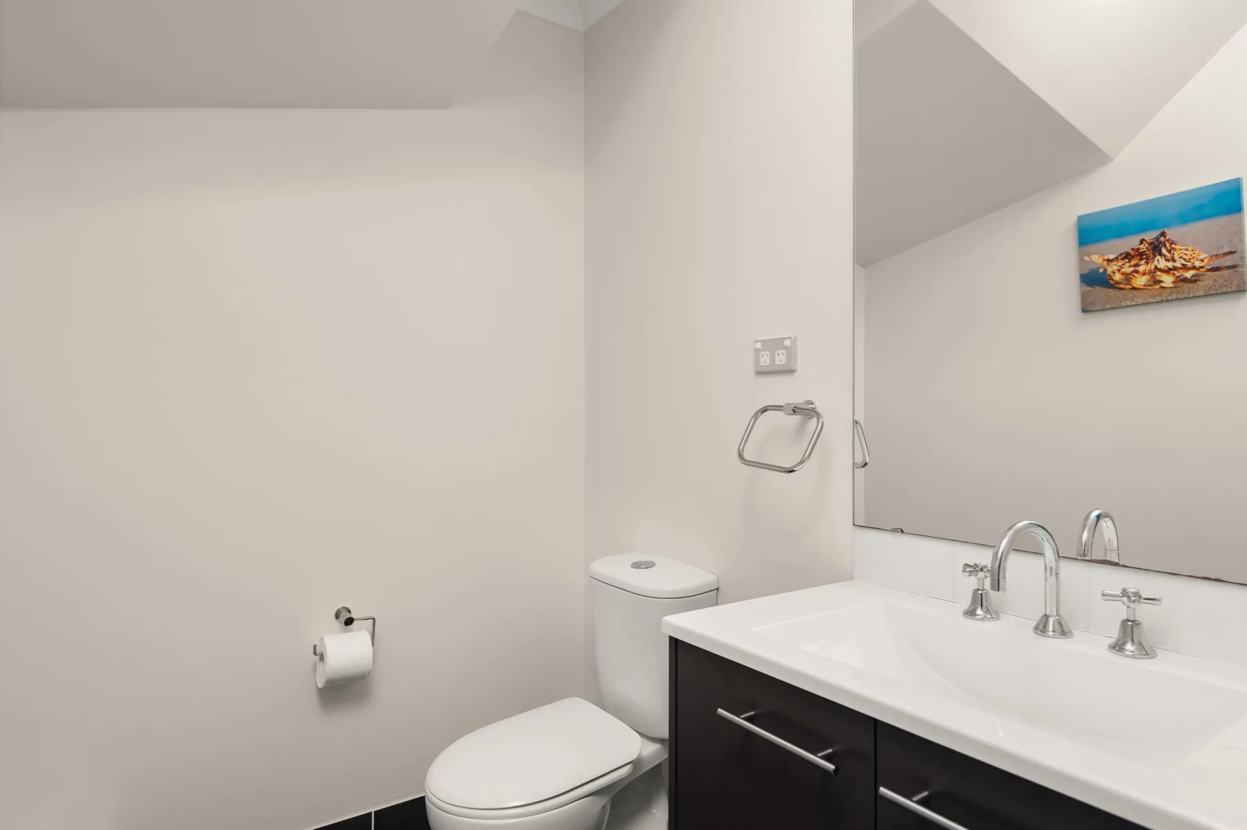 A bathroom with a toilet, sink, and wall mirror.