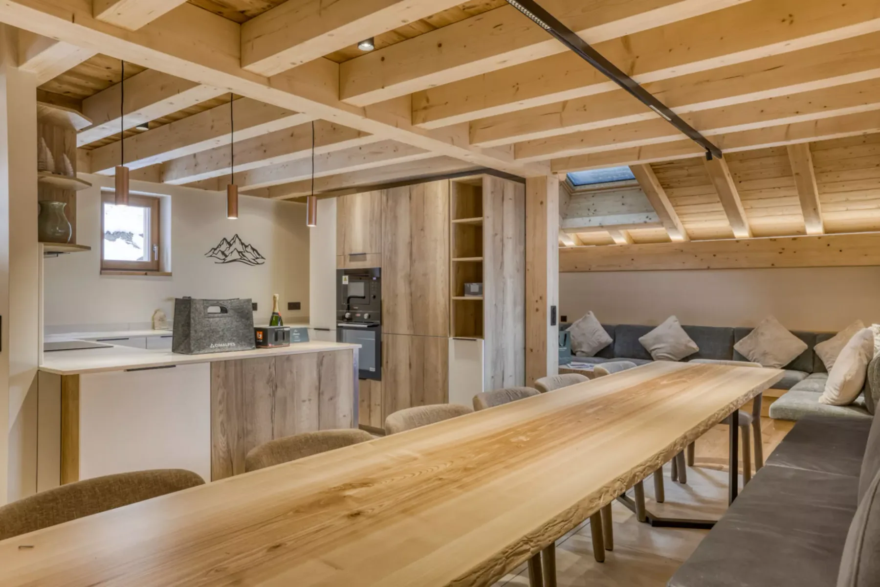 A wood-paneled open-plan living and dining area with a kitchen and long table.