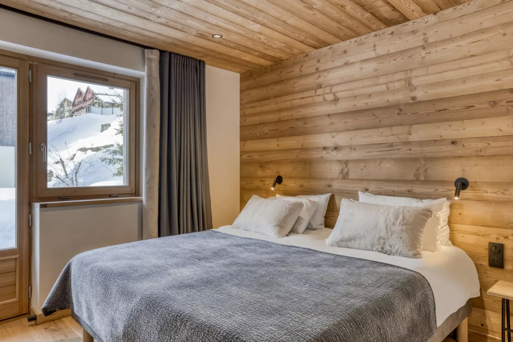 A bedroom with a bed beside a large window.