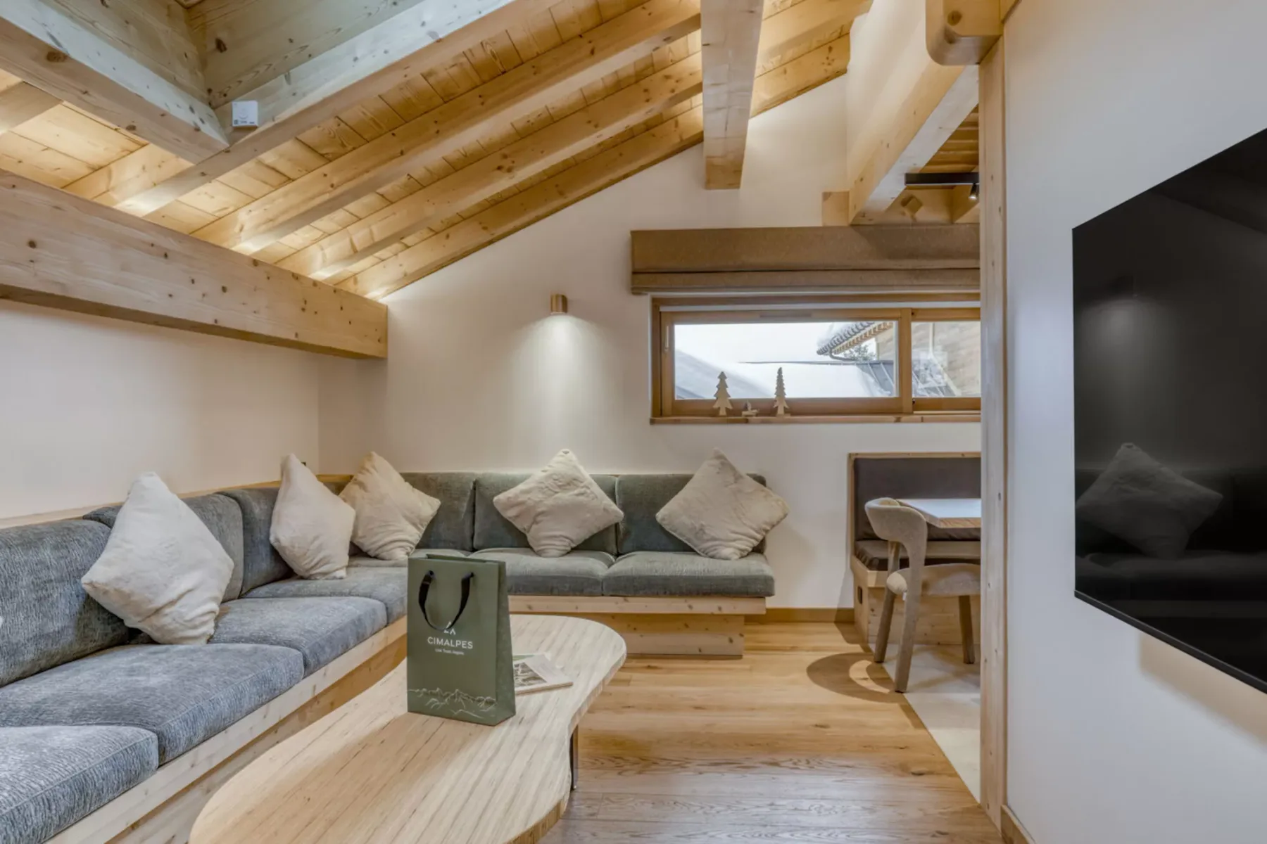 A living room with built-in seating, a wooden coffee table, and exposed ceiling beams.