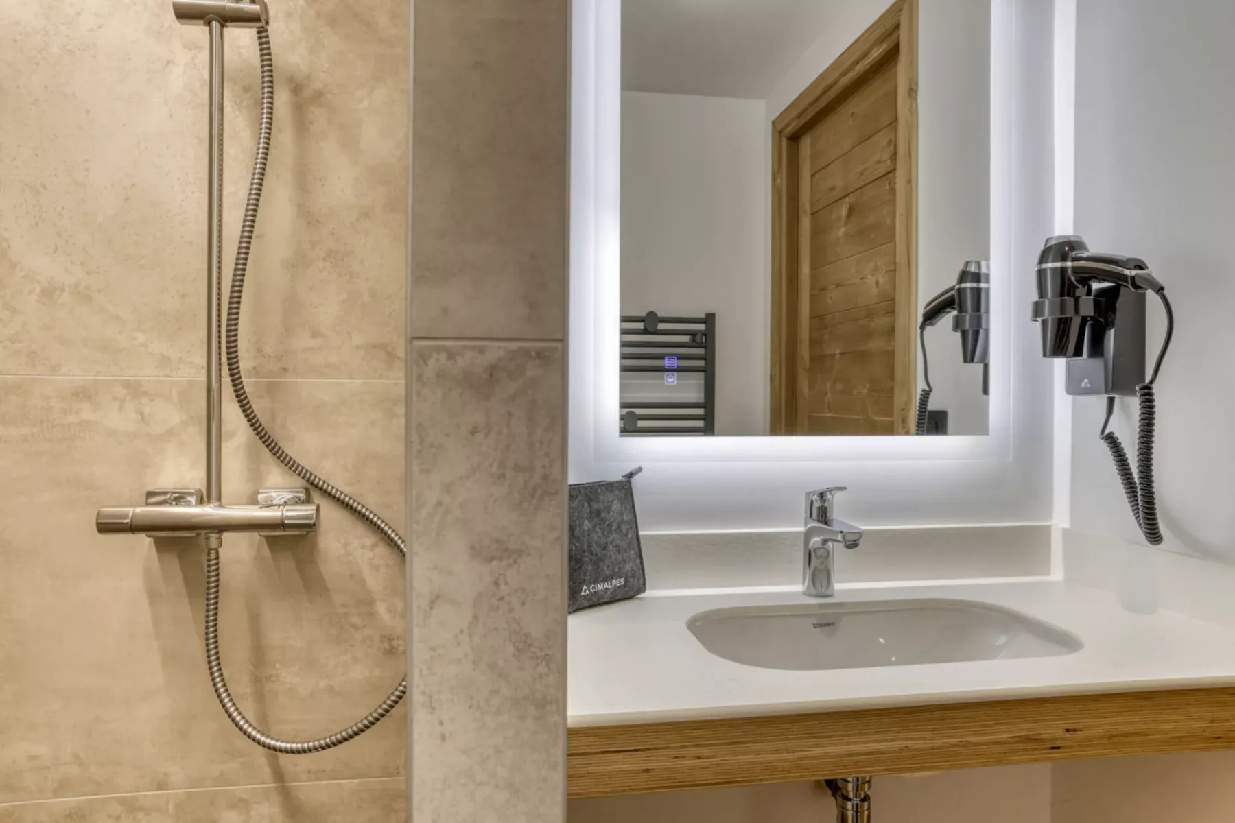 A bathroom with a sink, illuminated mirror, and shower.