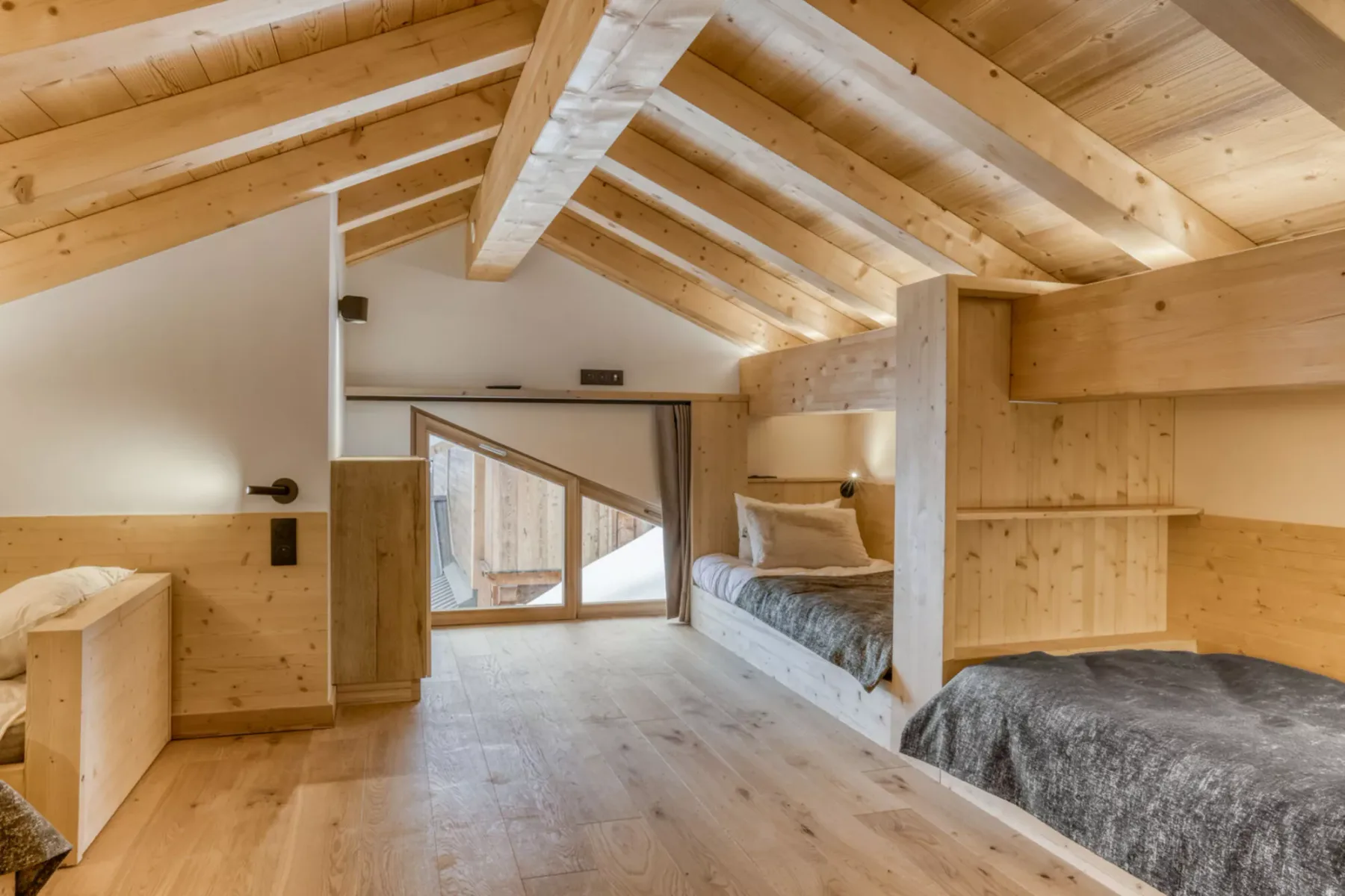 A wood-paneled loft bedroom with a bed beneath a sloped ceiling.