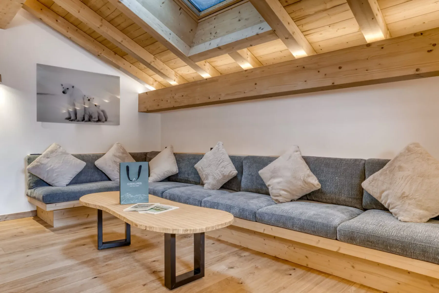 A living room with a long gray sectional, cushions, and a wooden coffee table.