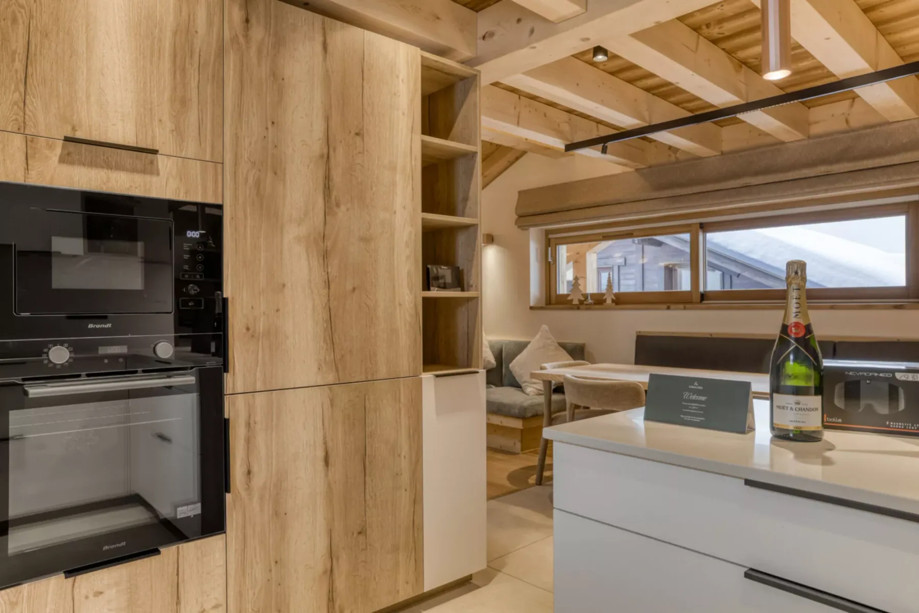 A wood-paneled kitchen opens onto a dining area beneath exposed timber beams.