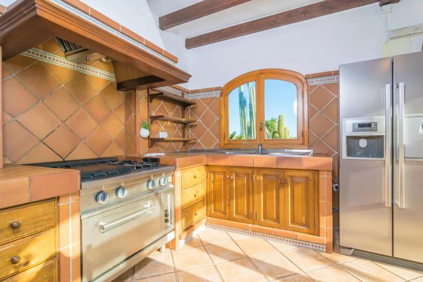 Una cocina con gabinetes de madera, una estufa y una ventana grande.